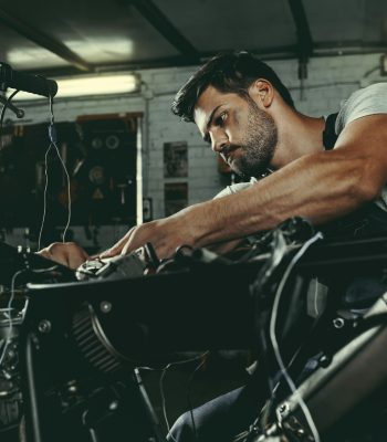 young handsome mechanic repairing motorbike in workshop